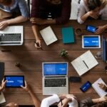 Overhead view of a diverse team in a business meeting using laptops and tablets.